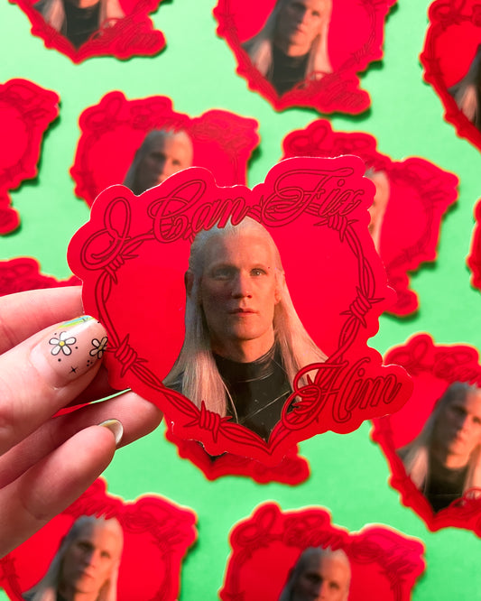 A person holding a vinyl sticker with an image of Daemon Targaryen, and other similar stickers visible in the background.
