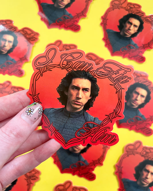 A person holding a vinyl sticker of Kylo Ren with the text 'I Can Fix Him' on a yellow background, where other similar stickers are also visible.