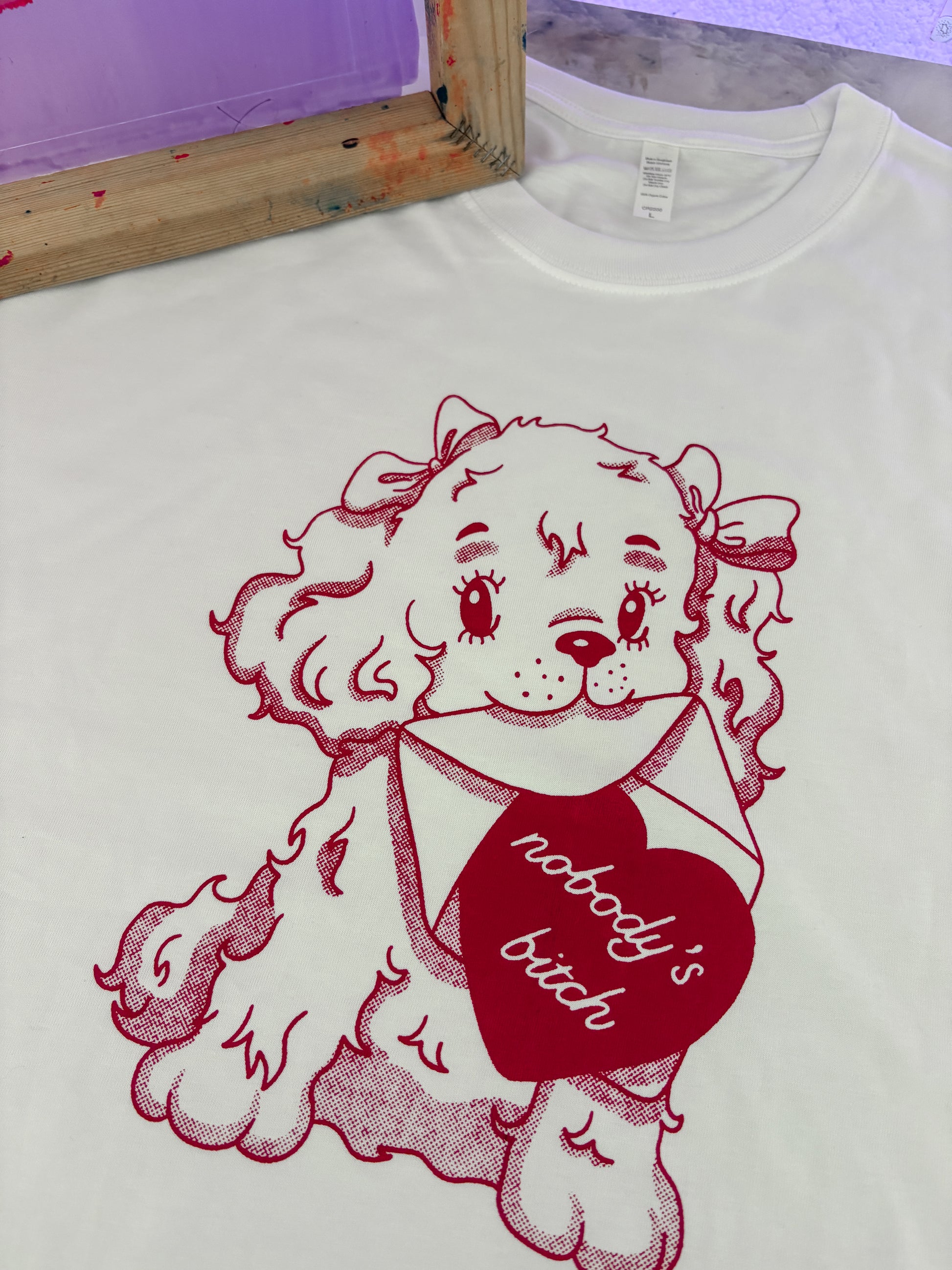 White t-shirt with red graphic of a dog holding a heart and text