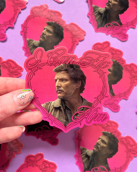 A person holding a vinyl sticker with an image of Pedro Pascal, with multiple stickers displayed in the background.