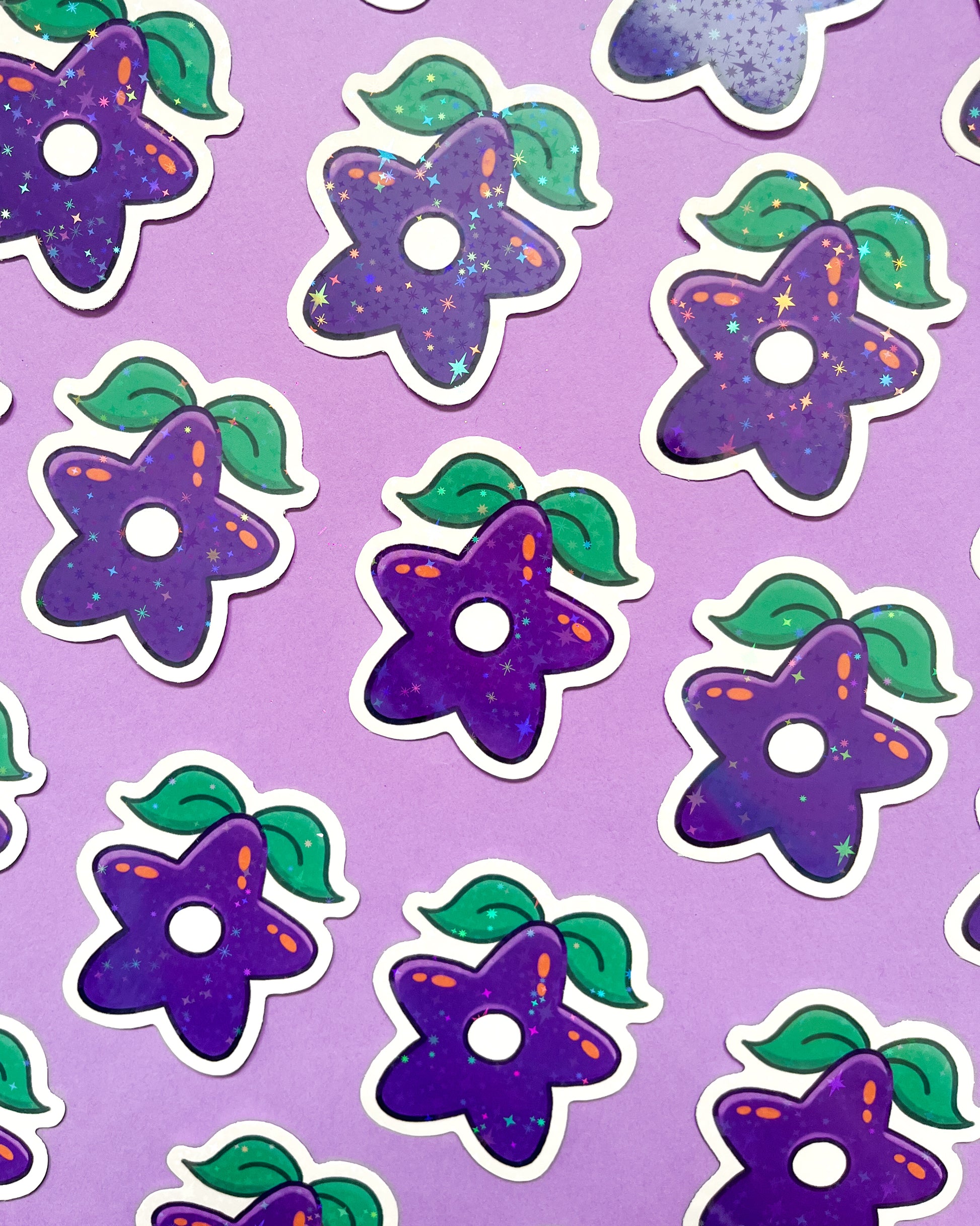 A collection of purple holographic vinyl stickers with a pattern of stars and leaves on a purple background.