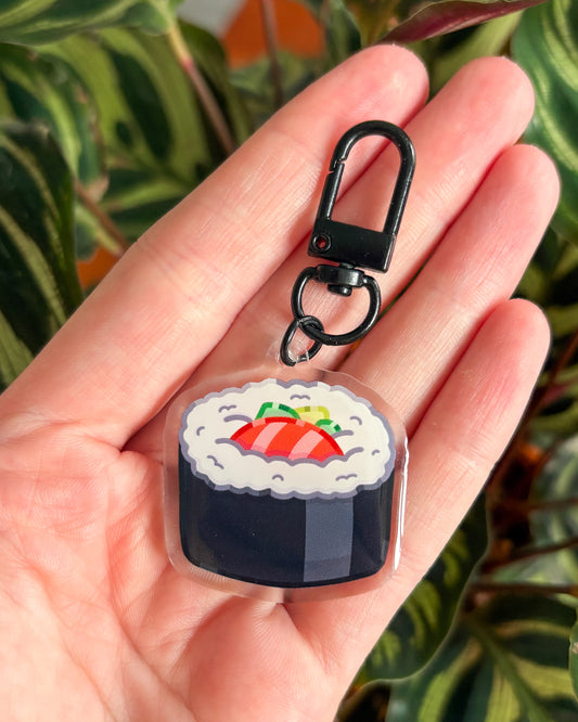 Sushi-shaped keychain held in a hand with a green leafy background