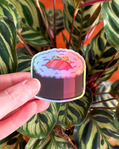Holographic sticker of sushi roll held in front of a leafy plant